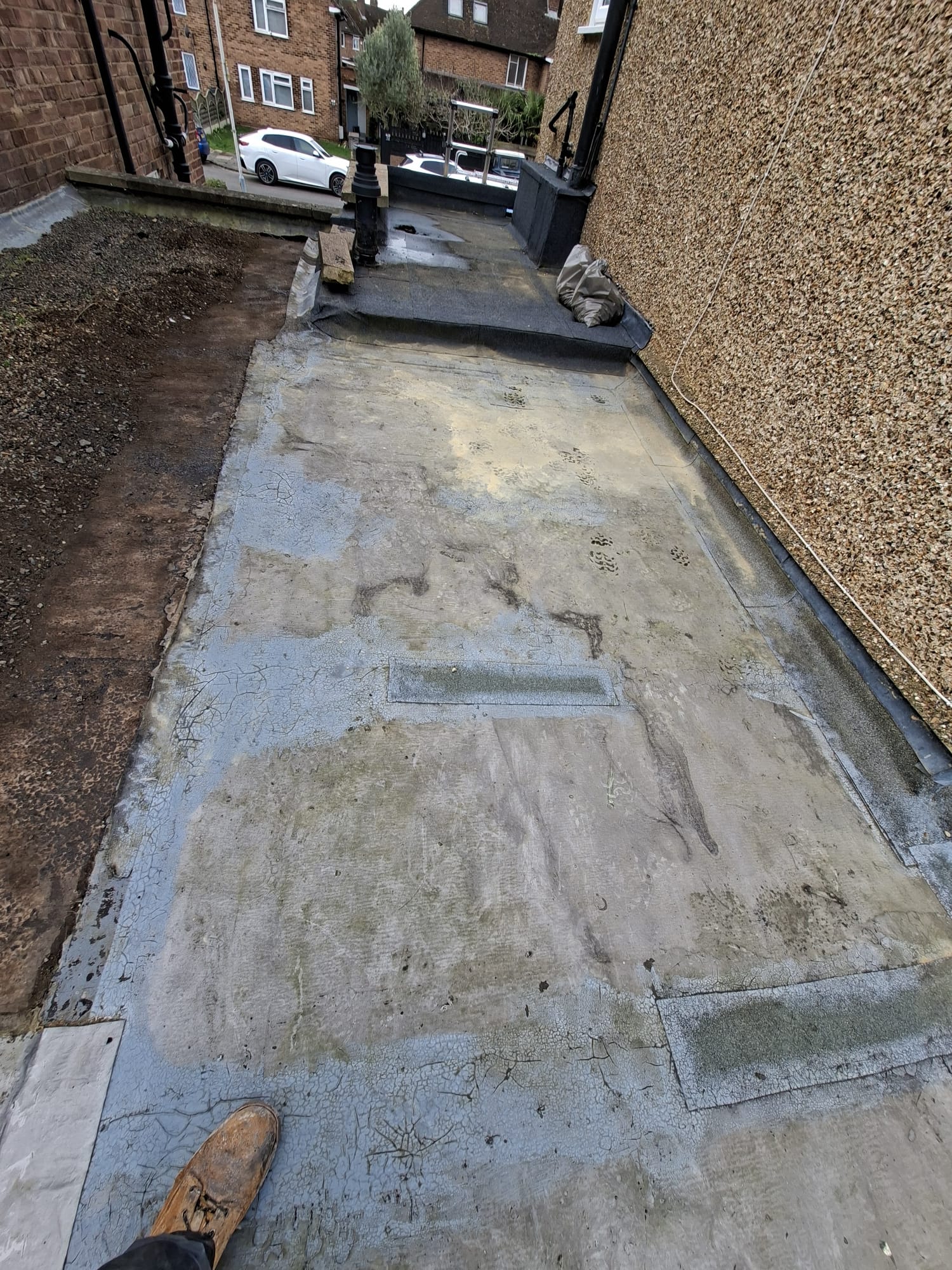 Damaged flat roof felt requiring repair — before photo