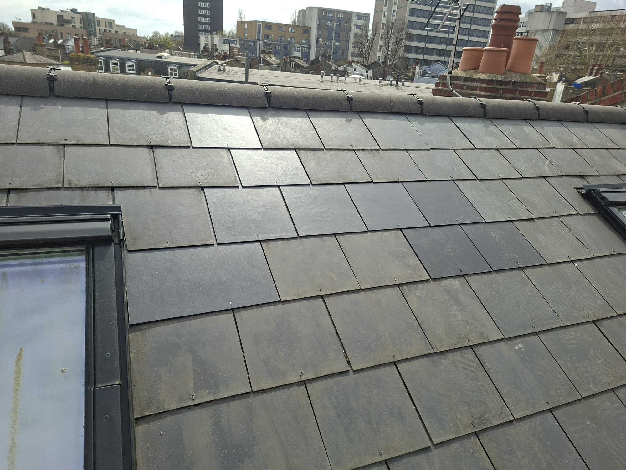 Slate roof with Velux skylight and London city backdrop